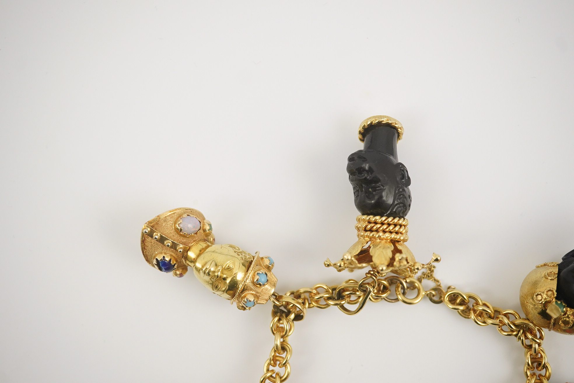 A late 20th century Italian 18k gold charm bracelet, hung with six assorted Italian 18k gold and gem set mounted blackamoor busts, together with a matching brooch